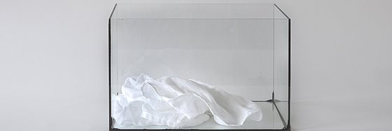 Ein Tuch liegt in einem Glaskasten.